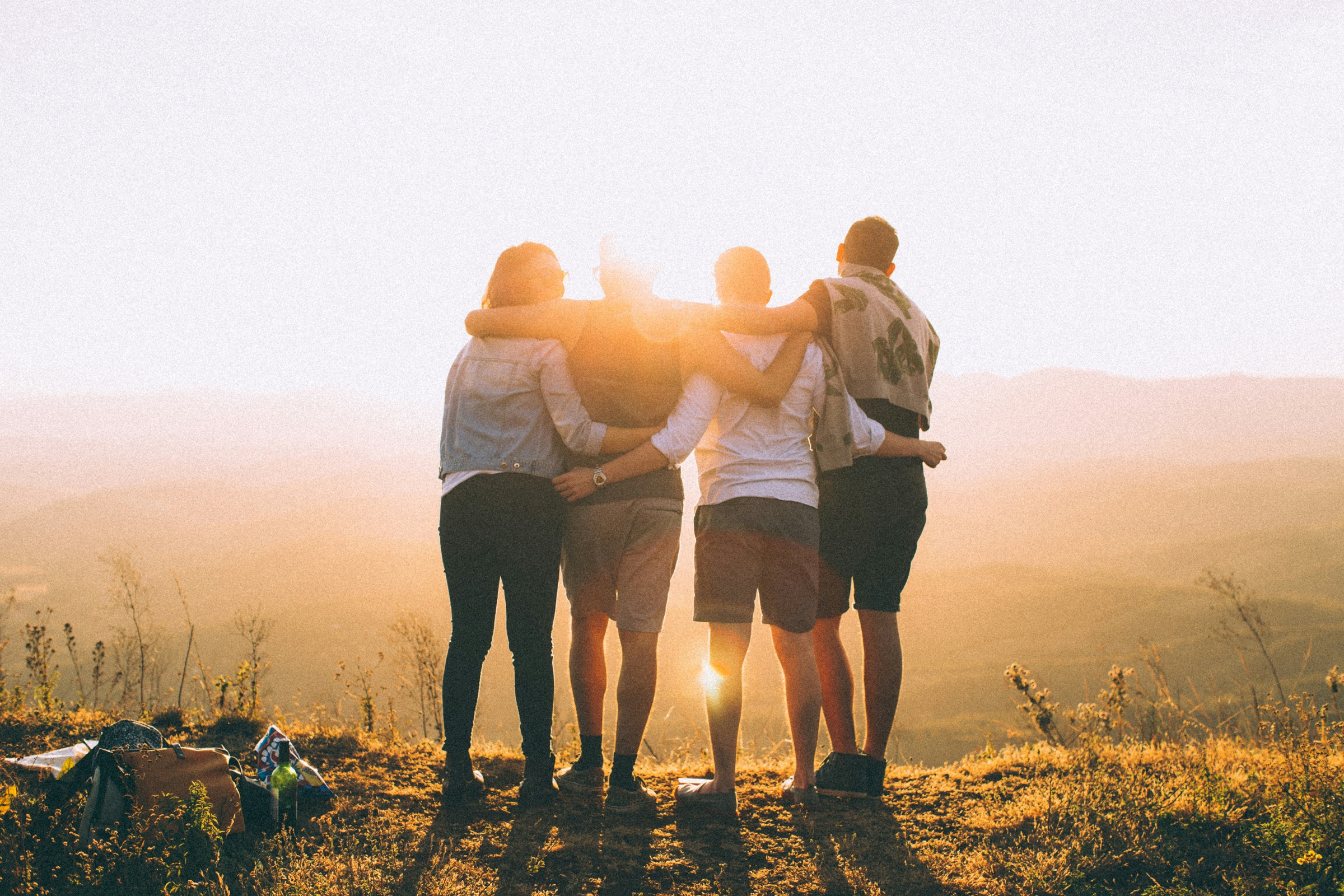 A group of friends watching the sunset over the hills together